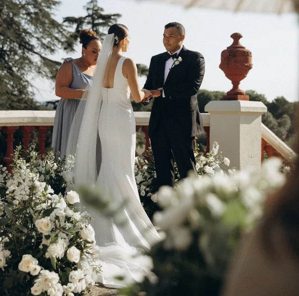 Arranjament floral amb flors de temporada en tons taronja, rosats i blancs, amb fullatge verd, per a la decoració d’un casament a l’exterior.
