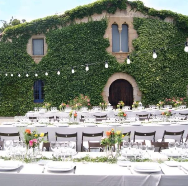 Vista de Masia Can Tosca amb una gran taula de comensals decorada per a un banquet de casament en un entorn natural i paisatgístic.