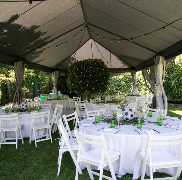 Carpa gran que cobreix tres taules rodones decorades amb estil per a un banquet de casament, creant un espai acollidor i elegant per als convidats.