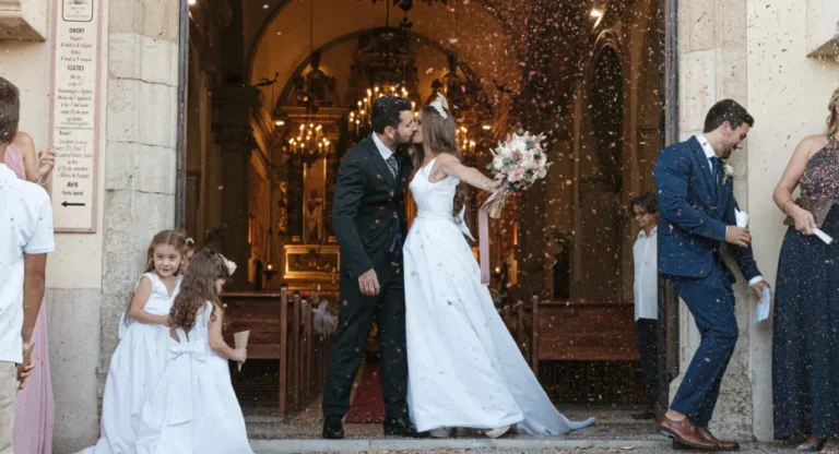 Novio y novia se besan durante la celebración de su boda, rodeados de invitados y un ambiente lleno de alegría y amor.