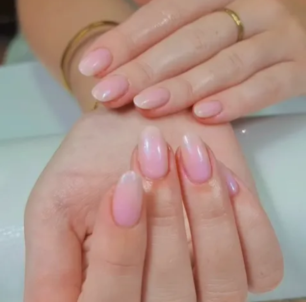 Primer pla d’unes mans amb manicura en tons rosats brillants i acabat natural, ideal per a un look de núvia elegant.